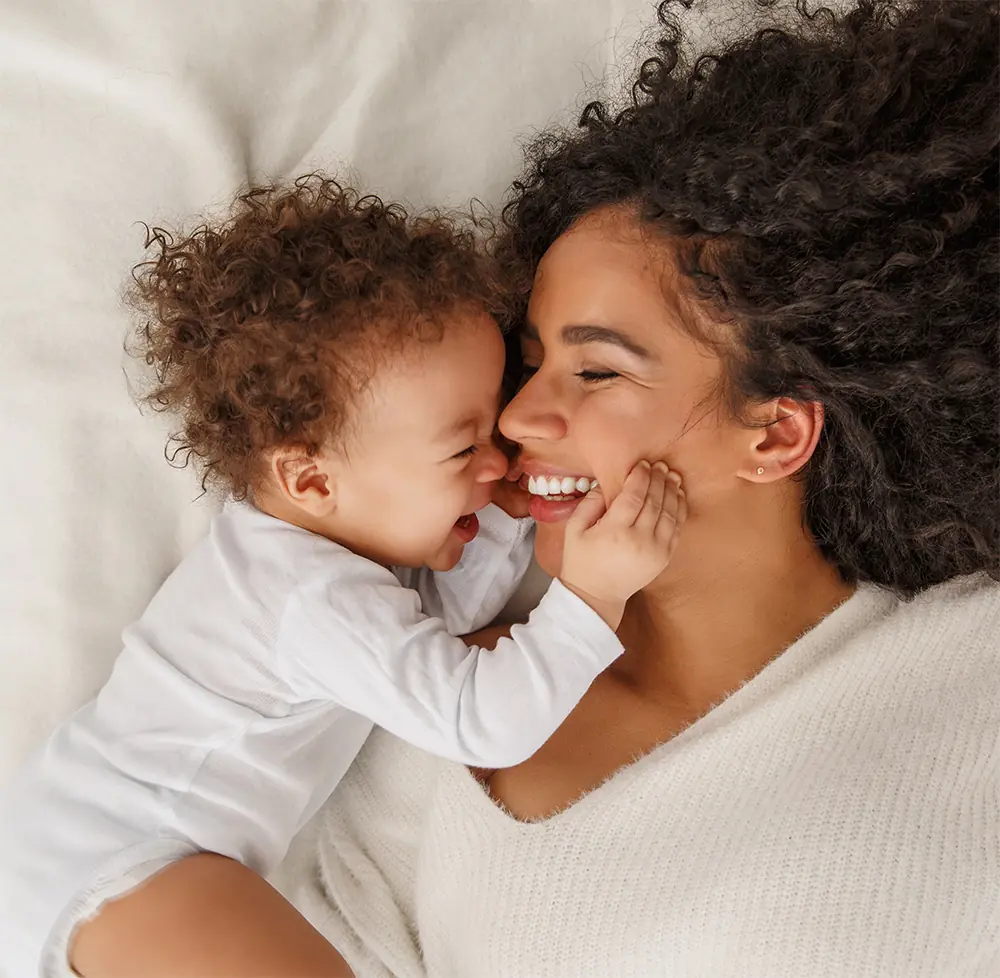 eine glückliche Mutter mit ihrem Baby, dunkle Haare, weiße Kleidung